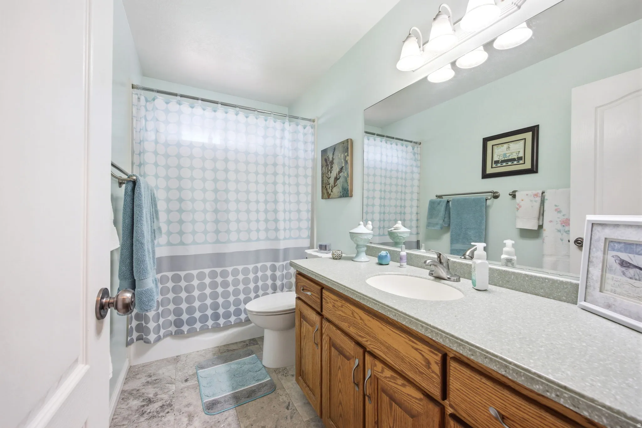 Bathroom featuring a wood-finish vanity with a single sink and light-colored countertop