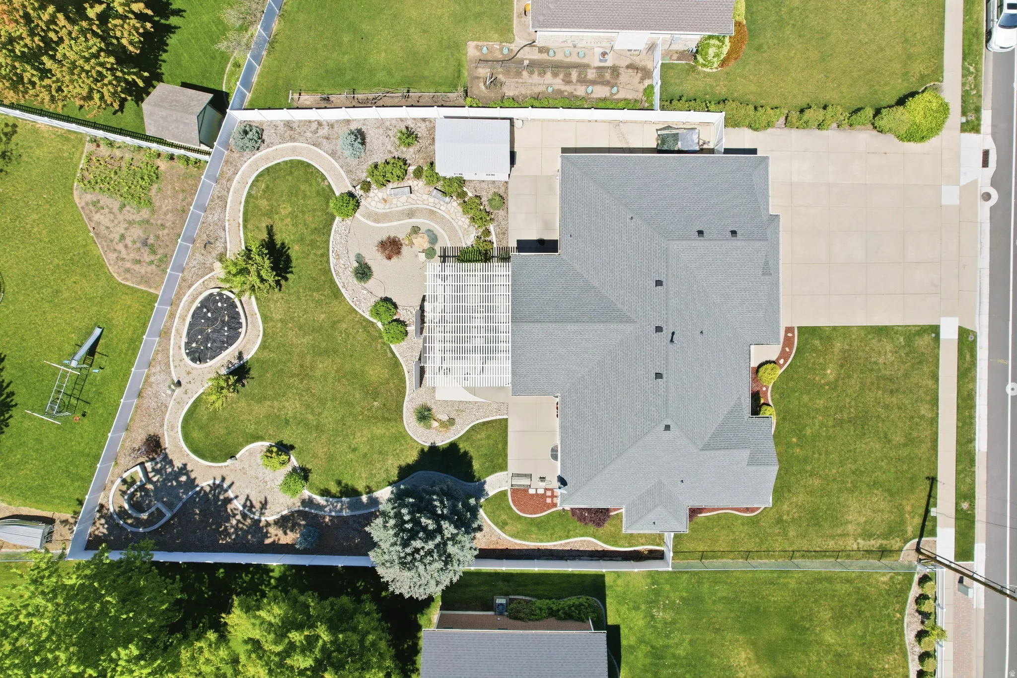 Expansive backyard featuring a manicured lawn, paved patio, and decorative stone pathways
