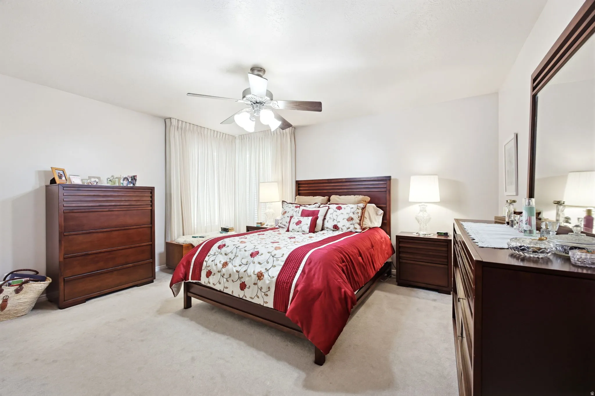 Spacious bedroom featuring light-toned carpet flooring, white walls, and a ceiling fan with integrated lighting