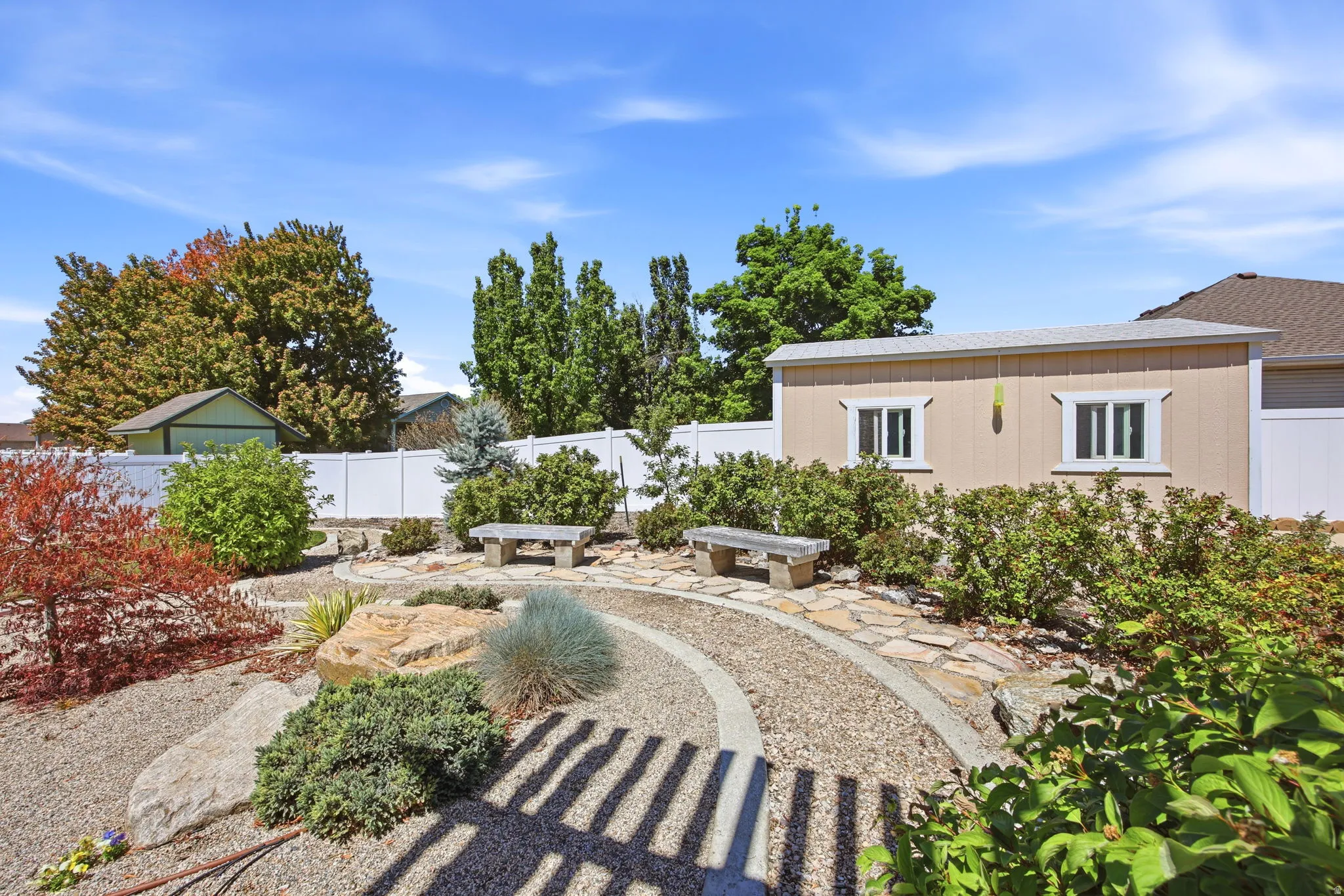 Expansive xeriscaped backyard featuring a gravel path, natural stone pavers, and mature plantings