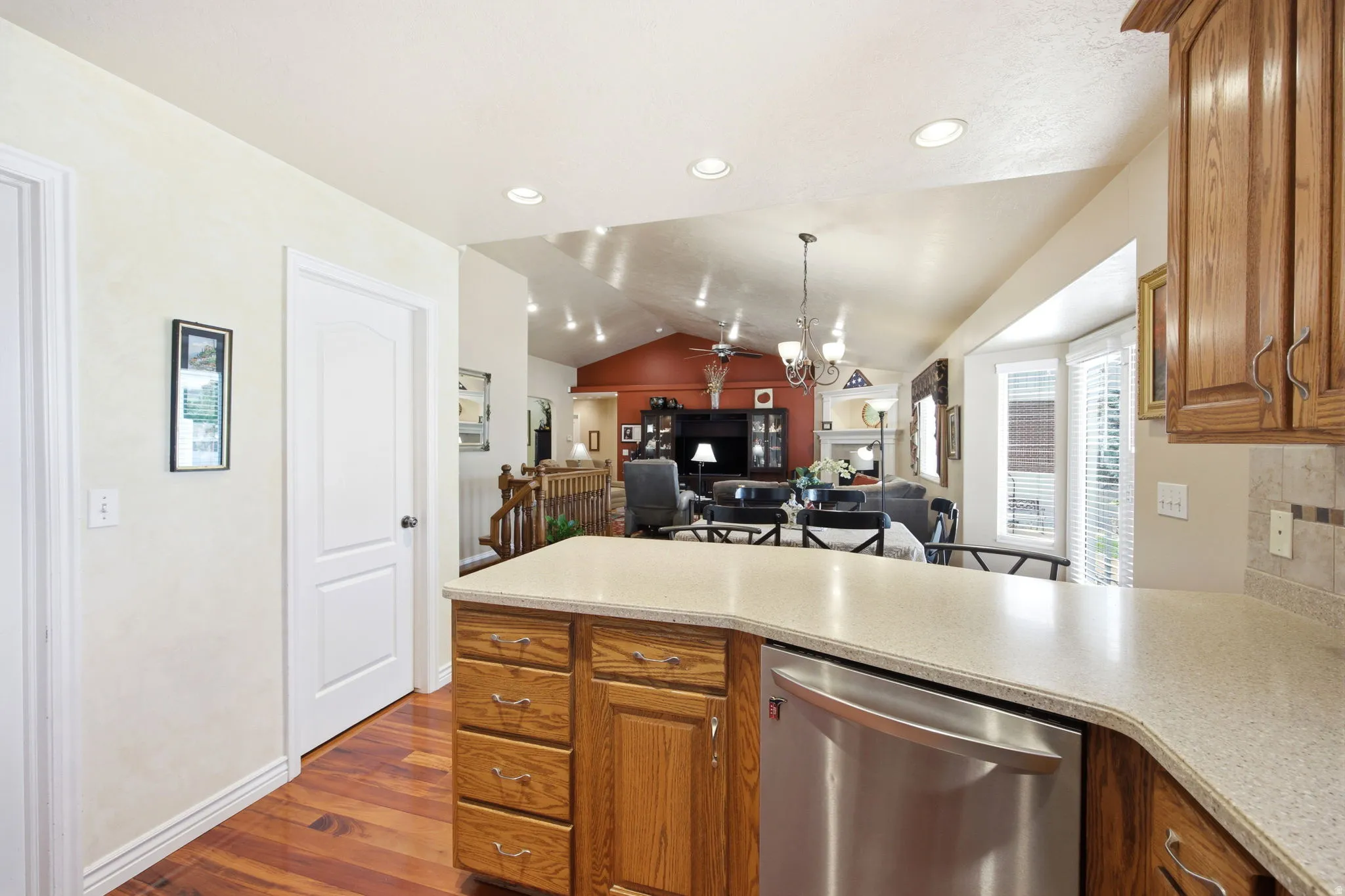Kitchen peninsula featuring a light-toned countertop, wood-finish cabinetry, and a stainless steel dishwasher