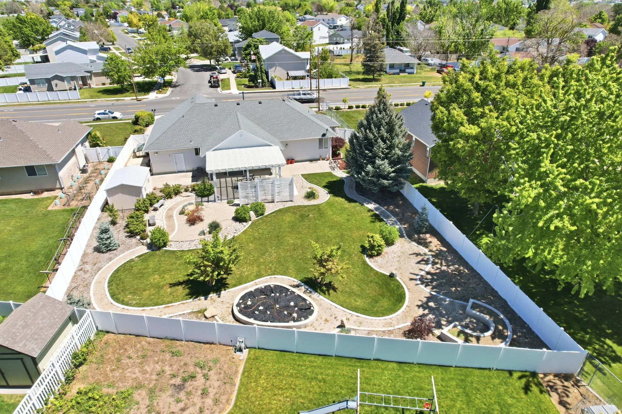 Expansive backyard featuring a manicured lawn, established landscaping, and decorative stone pathways