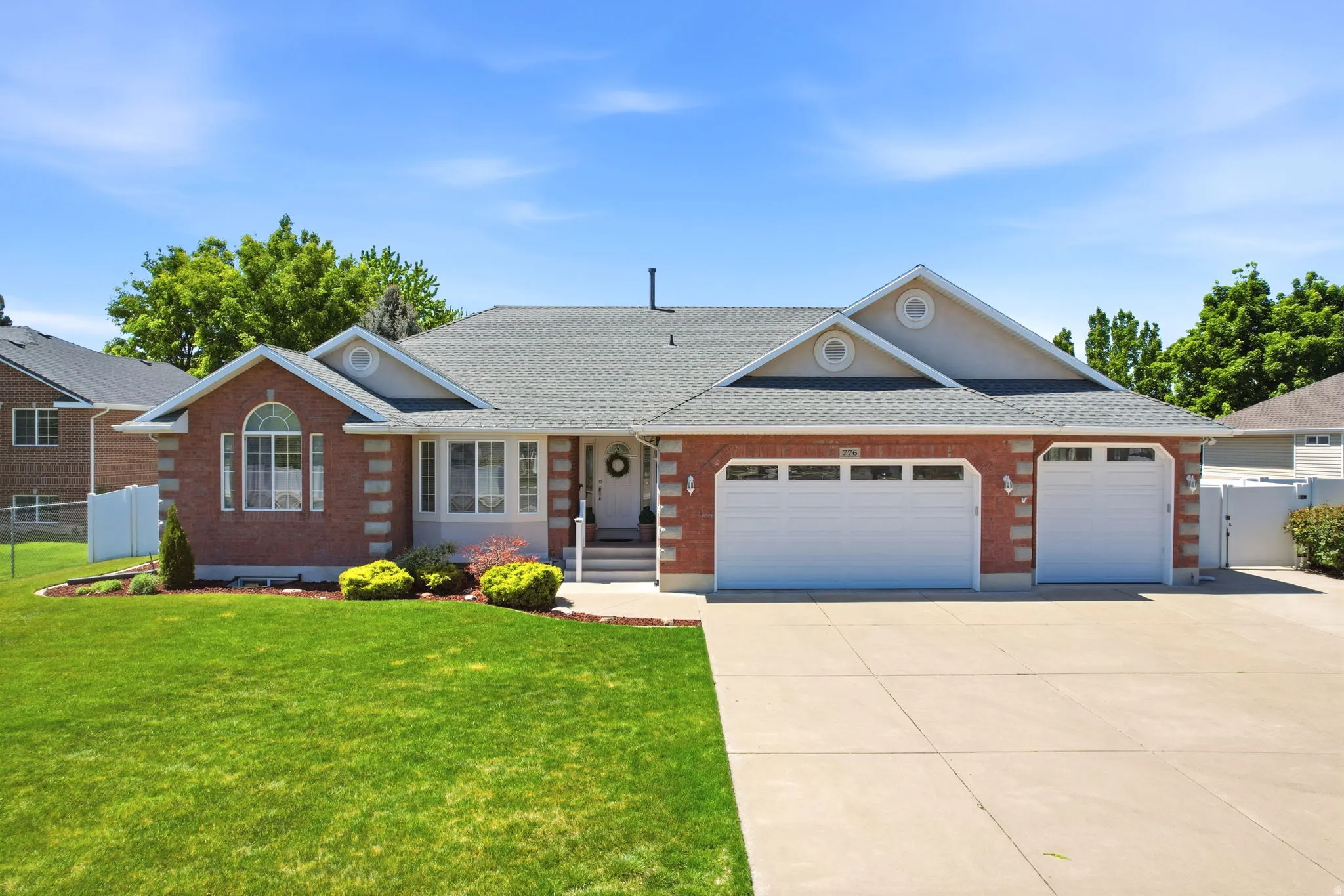 Traditional-style residence featuring a brick facade with stone accents, a gray shingled roof, a concrete driveway, and an attached two-car garage