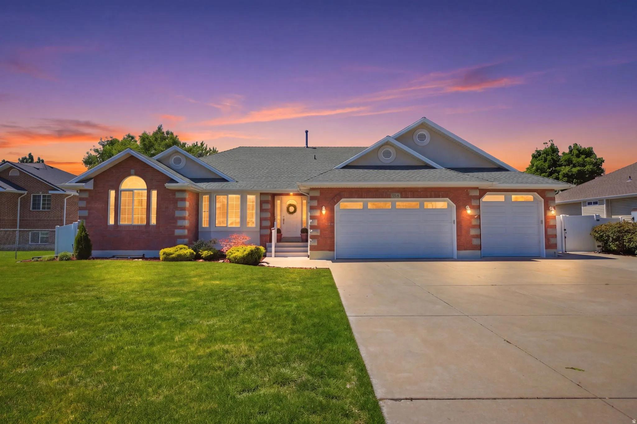 Brick facade residence with a two-car garage, concrete driveway, and a manicured front lawn