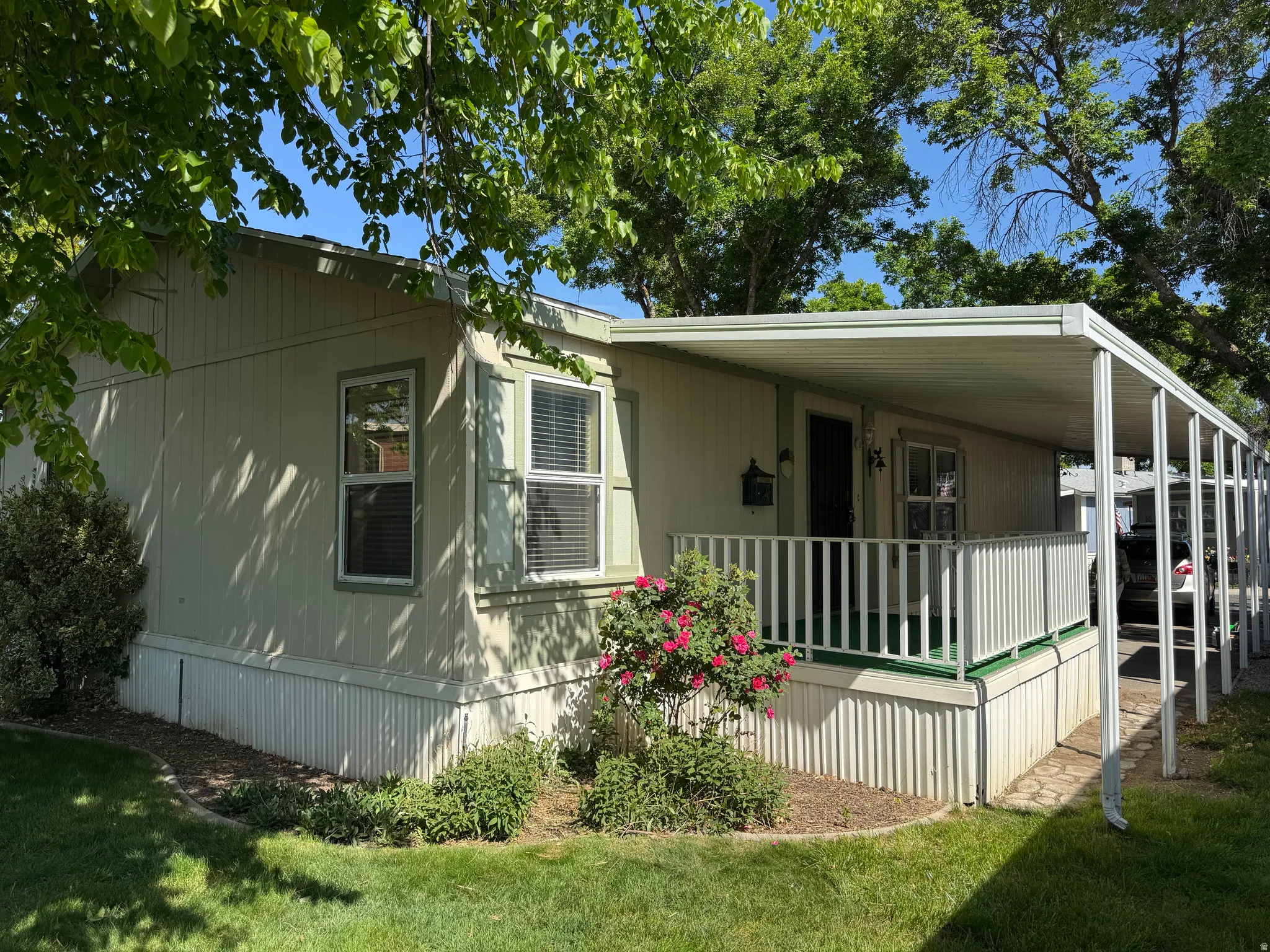 Front exterior featuring an extended covered porch, white railing, and a mature rose bush