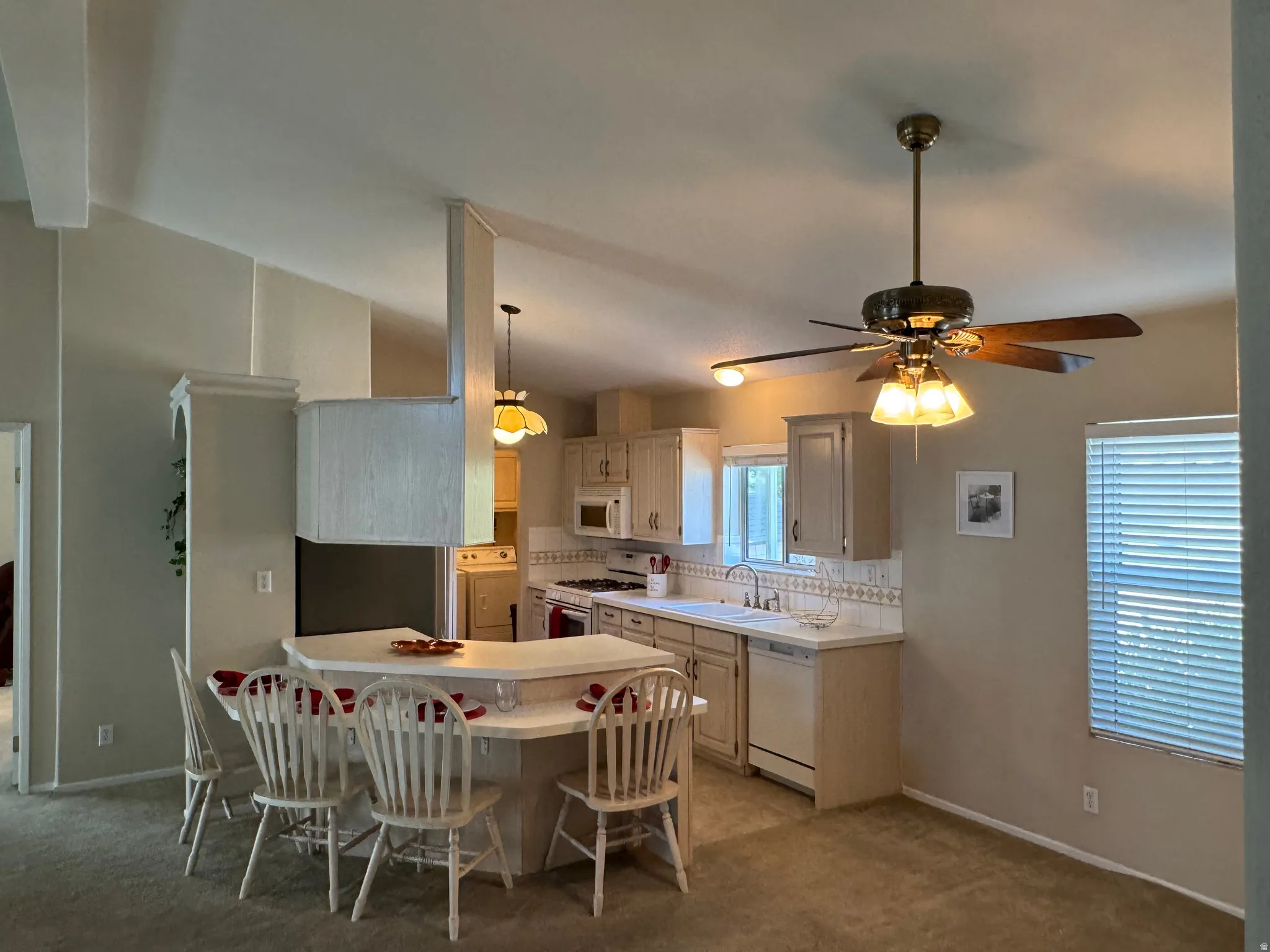 Open-concept kitchen featuring light-toned cabinetry, a built-in breakfast bar, white countertops, and a tiled backsplash