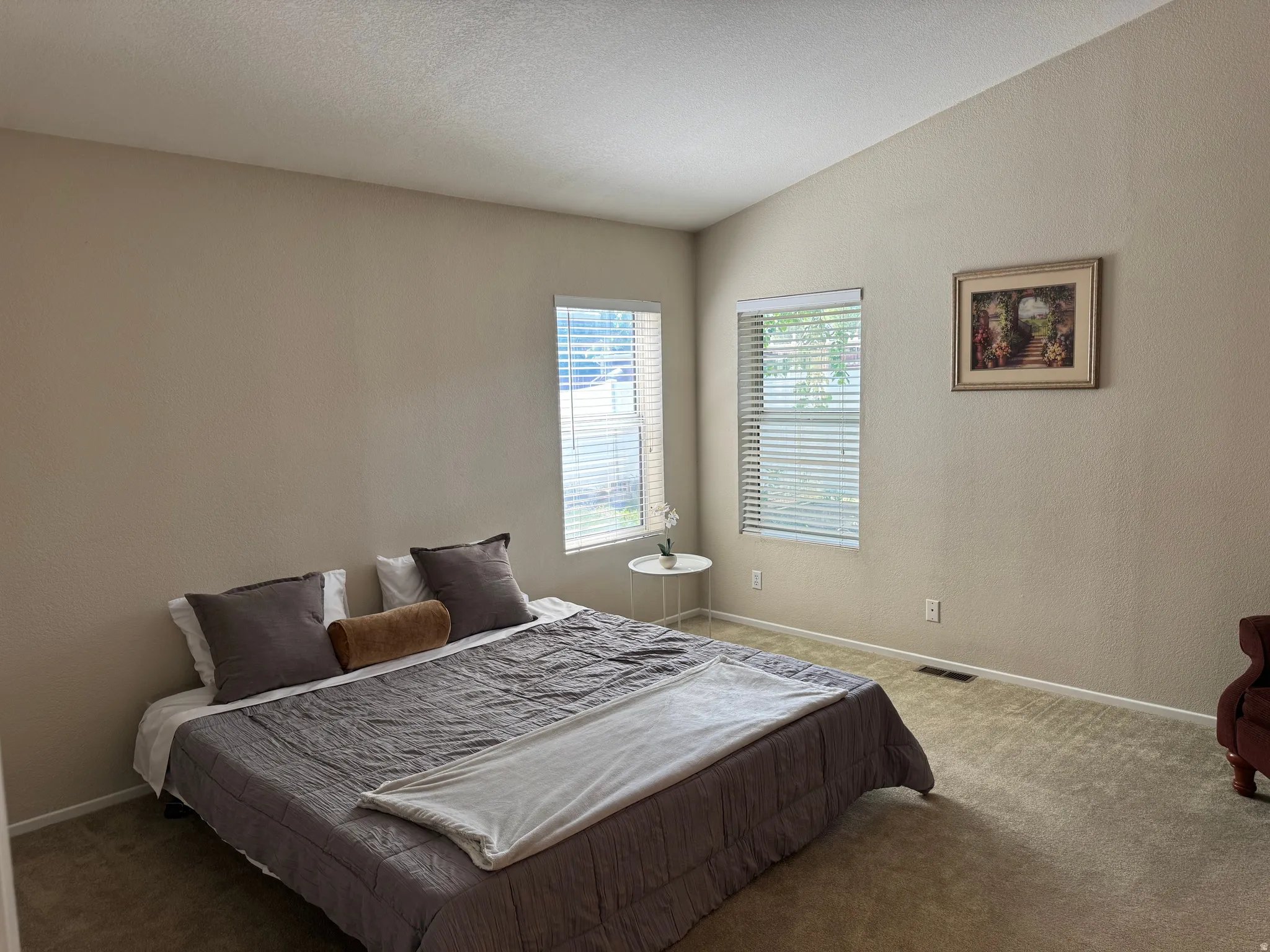 Room featuring two windows with horizontal blinds, neutral wall paint, and light-colored carpet flooring