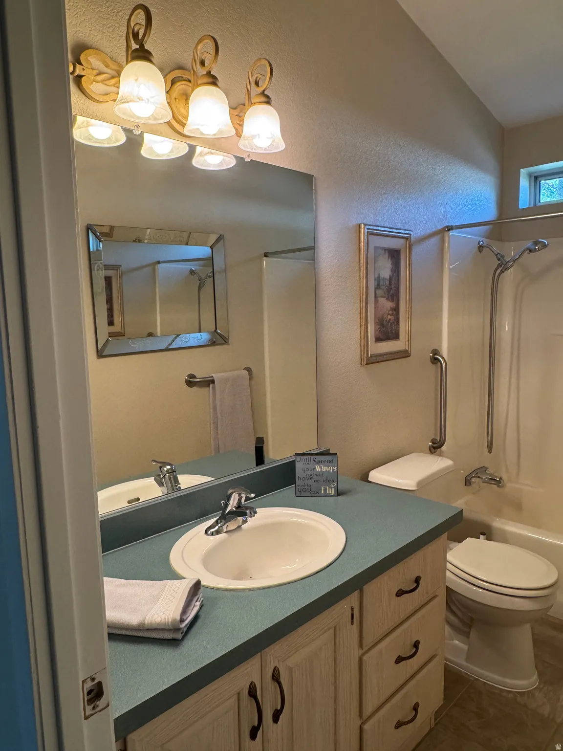 Bathroom featuring a single vanity with a laminate countertop, integrated sink, and an overhead vanity light fixture