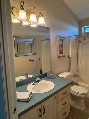 Bathroom featuring a single vanity with a laminate countertop, integrated sink, and an overhead vanity light fixture