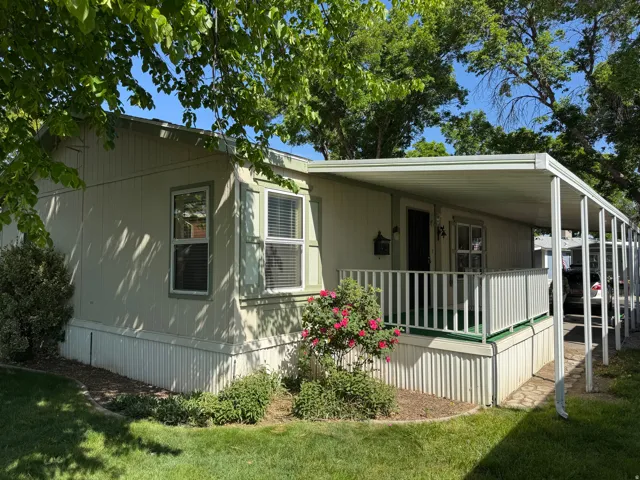 Front exterior featuring an extended covered porch, white railing, and a mature rose bush