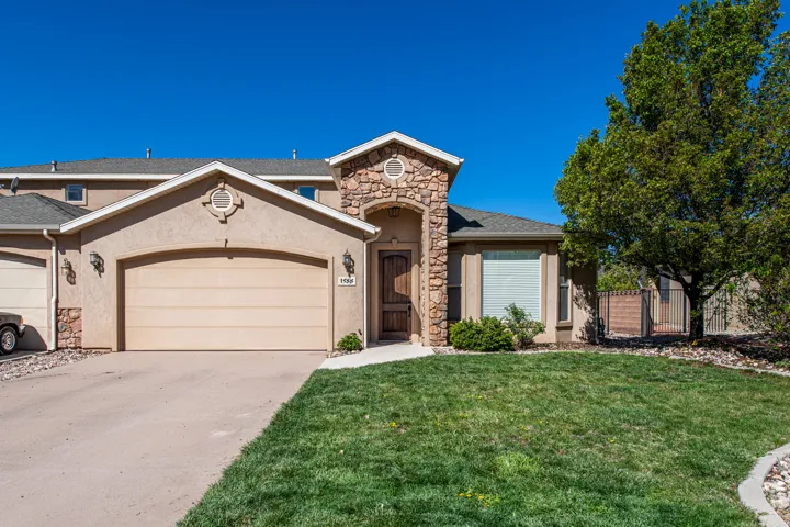 Stucco facade residence featuring a prominent stone archway entry