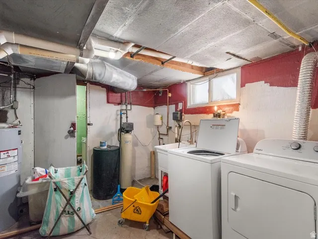 Dedicated utility area featuring a window, exposed ceiling joists, and visible plumbing