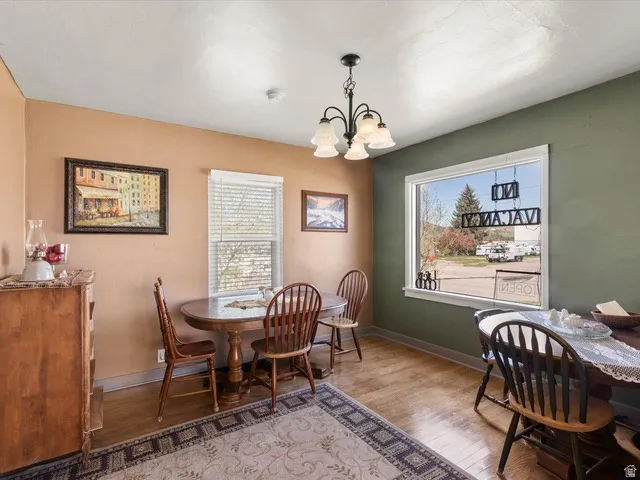 Room featuring wood-finish flooring, a contemporary chandelier, two large windows with blinds, and two-tone wall paint