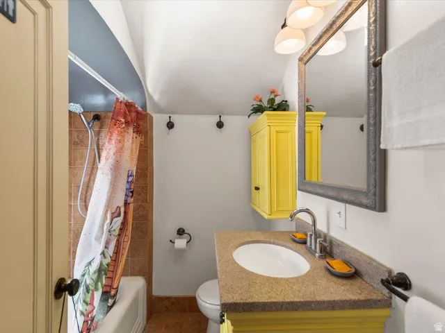 Bathroom featuring a built-in tub with tile surround, a vanity with a light-toned countertop, an integrated sink, a wall-mounted mirror, and overhead lighting