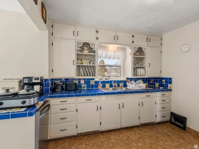 Kitchen featuring white cabinetry with dark hardware and a window above the sink