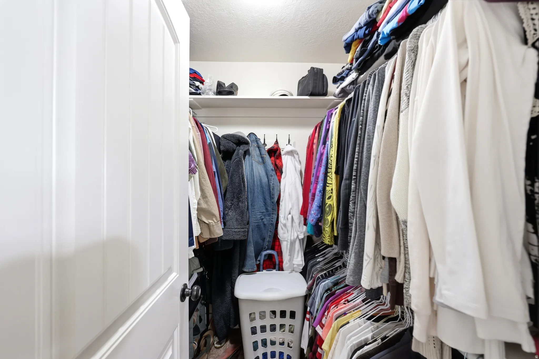 Walk-in closet featuring white shelving and chrome hanging rods