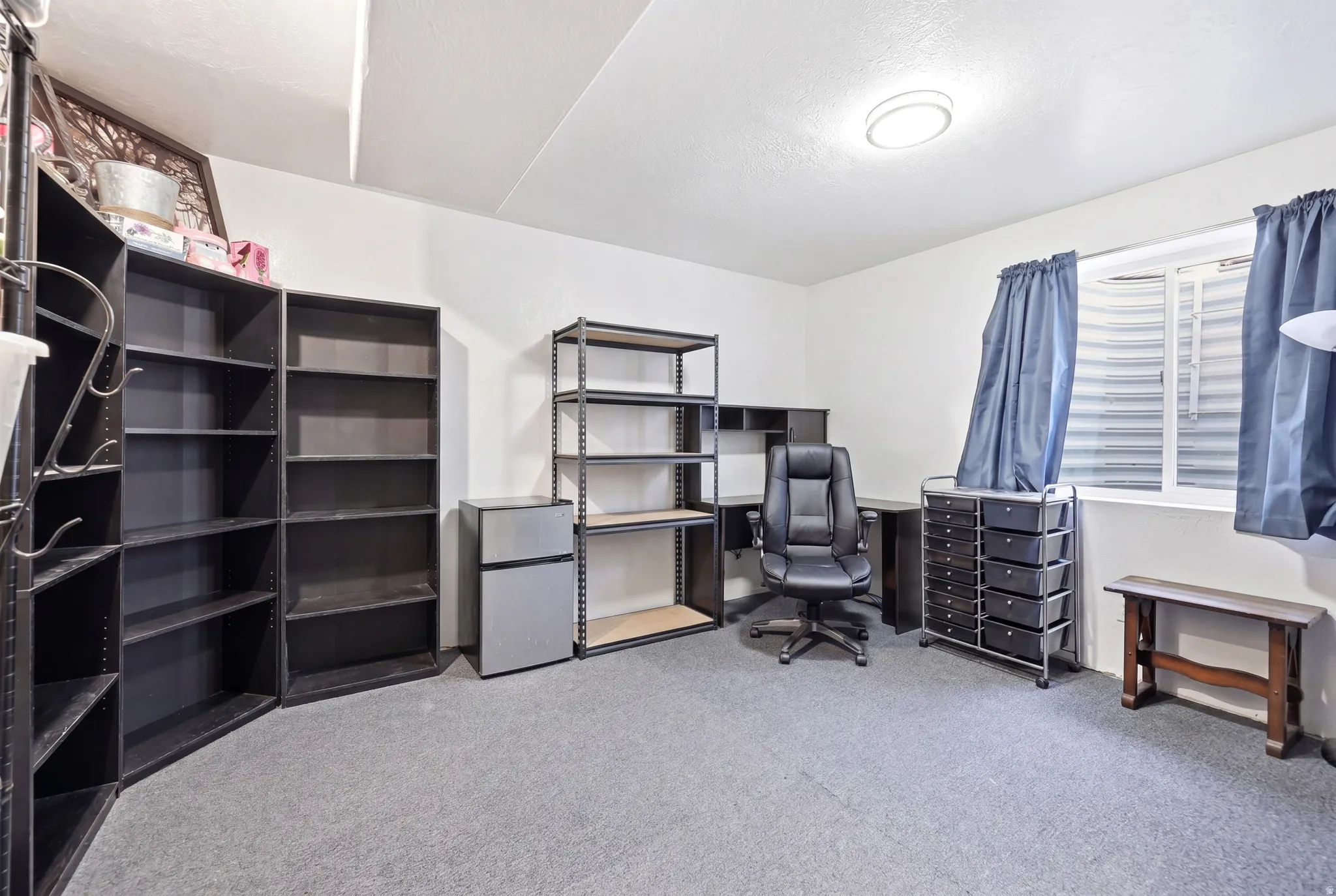 Flexible space featuring carpet flooring, a ceiling-mounted light fixture, and a window with blinds