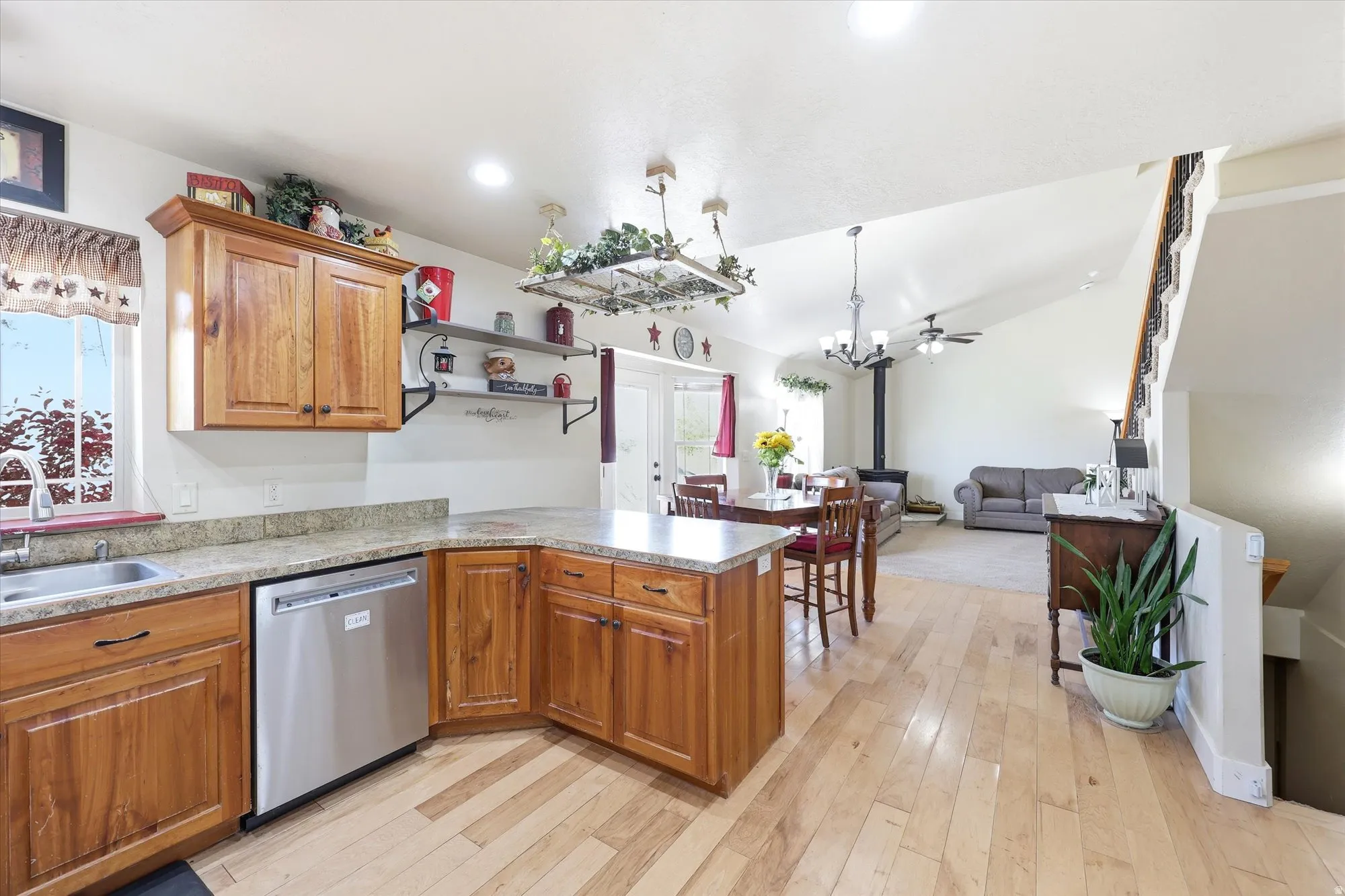 Open-concept kitchen featuring wood-finish cabinetry, a stainless steel dishwasher, and stone-finish countertops