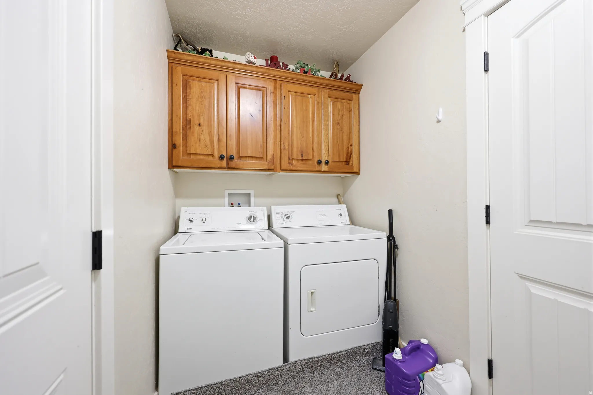Laundry area featuring light wood cabinetry, white interior doors, and a neutral wall color