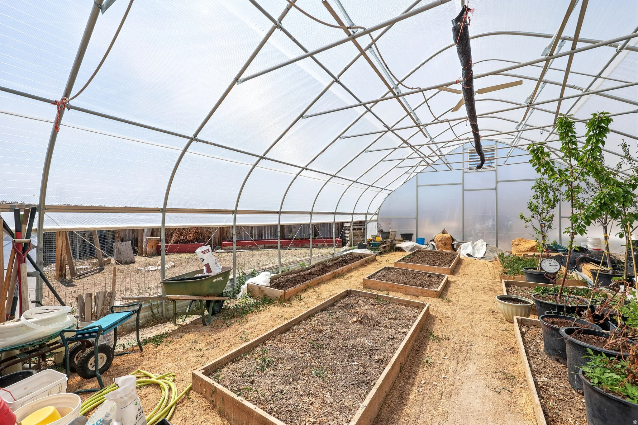 Spacious greenhouse structure with a translucent arched roof, metal frame construction, and multiple raised planting beds