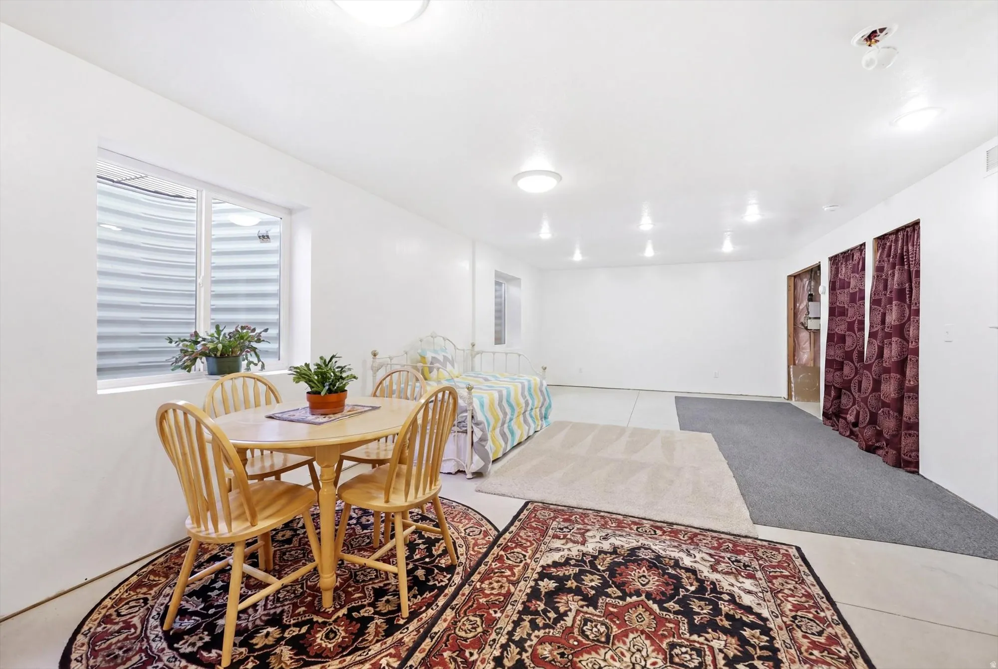 Spacious room featuring white walls, ample overhead lighting, and a large window