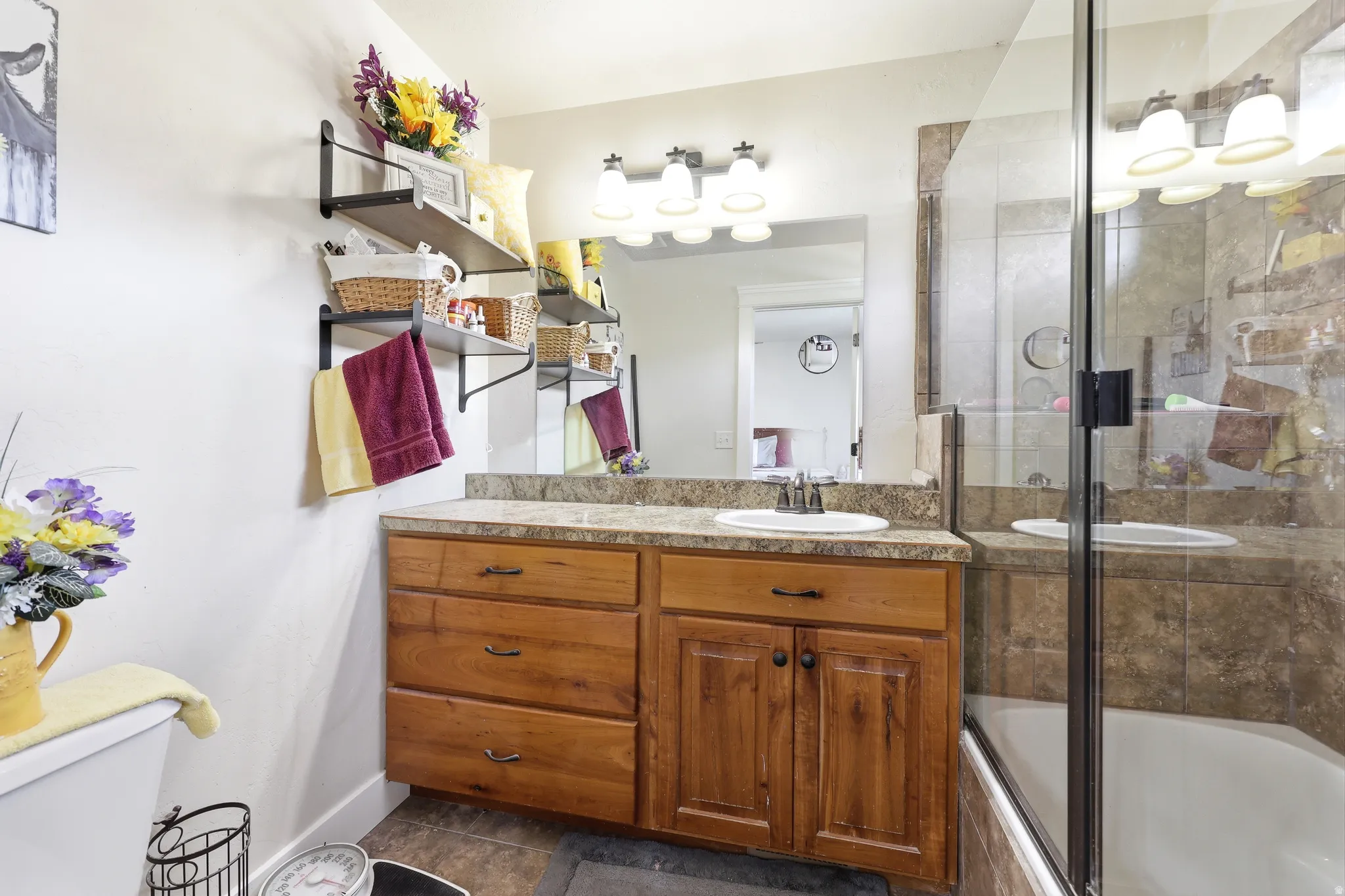 Bathroom featuring a wood-finish vanity with a single sink, an integrated mirror, and a three-light fixture