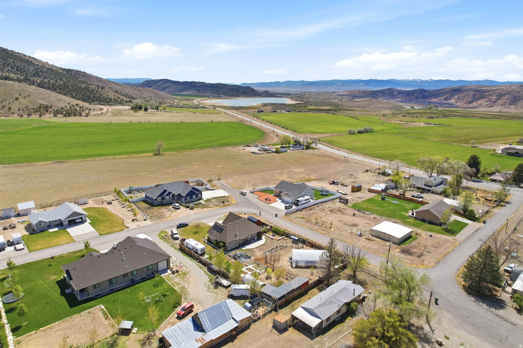 Rural neighborhood featuring expansive green fields, distant mountains, and a visible body of water