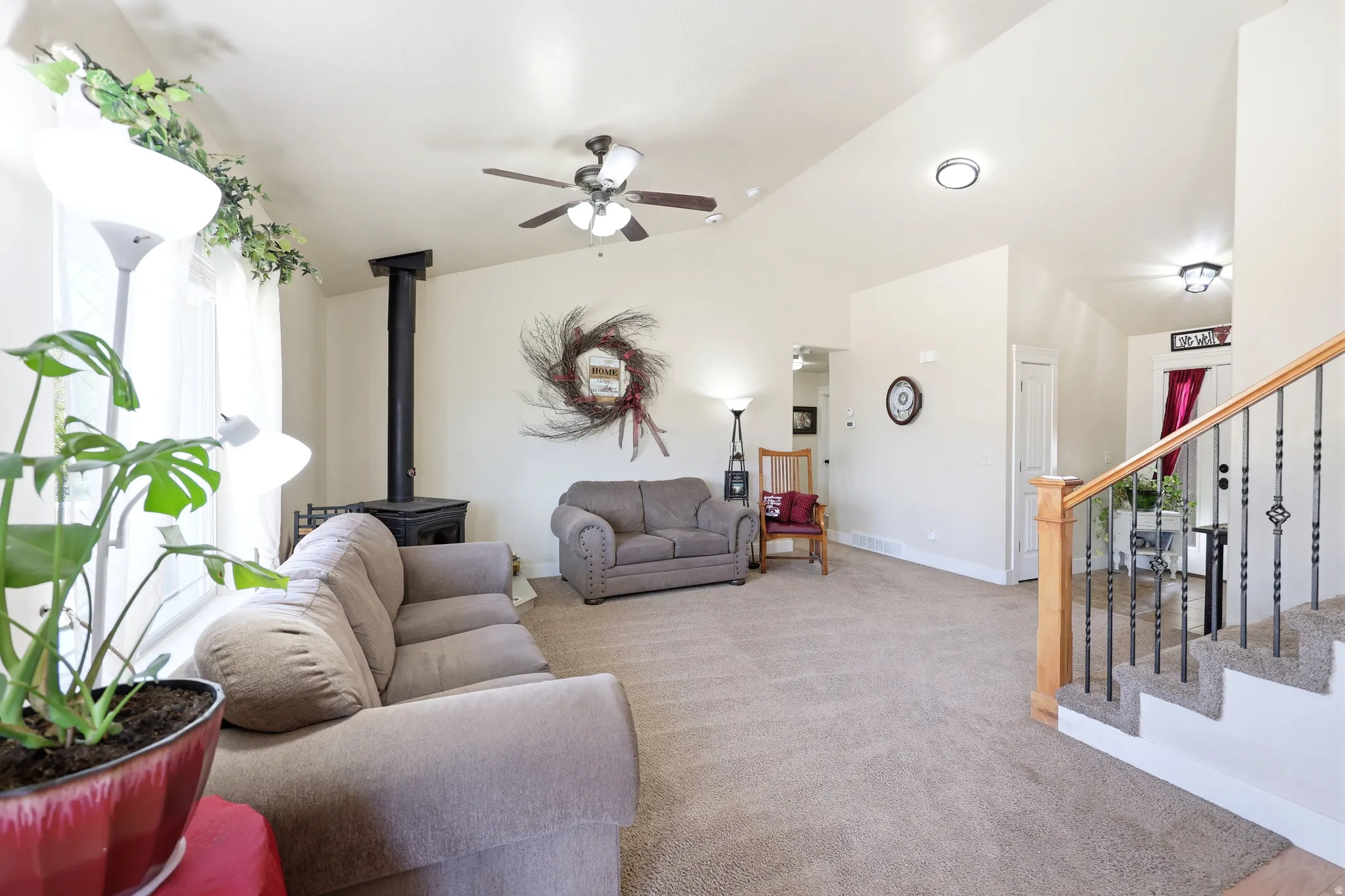 Carpeted living area featuring a wood-burning stove with a black stovepipe, a ceiling fan, and recessed lighting