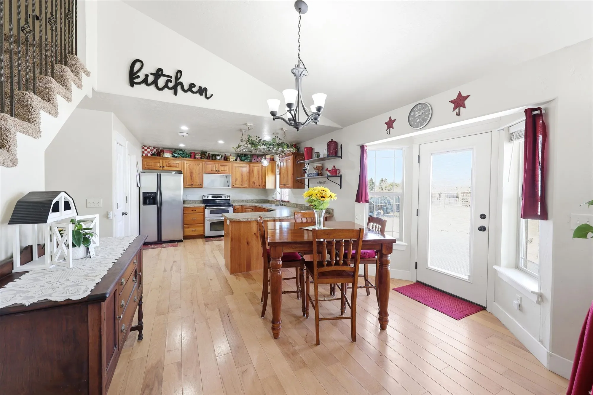 Open-concept kitchen and dining area featuring wood-finish flooring, recessed lighting, and a vaulted ceiling