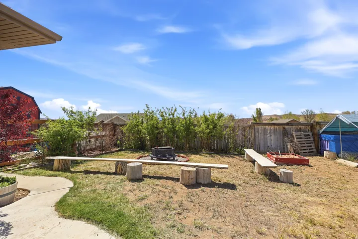 Expansive backyard featuring a fire pit, wood benches, and a concrete pathway