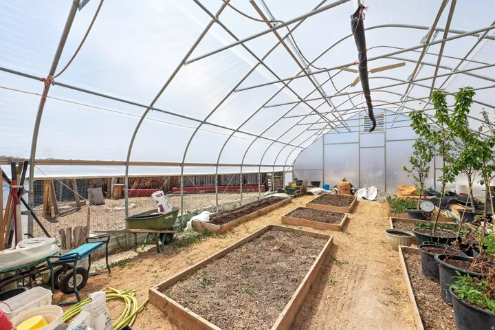 Spacious greenhouse structure with a translucent arched roof, metal frame construction, and multiple raised planting beds