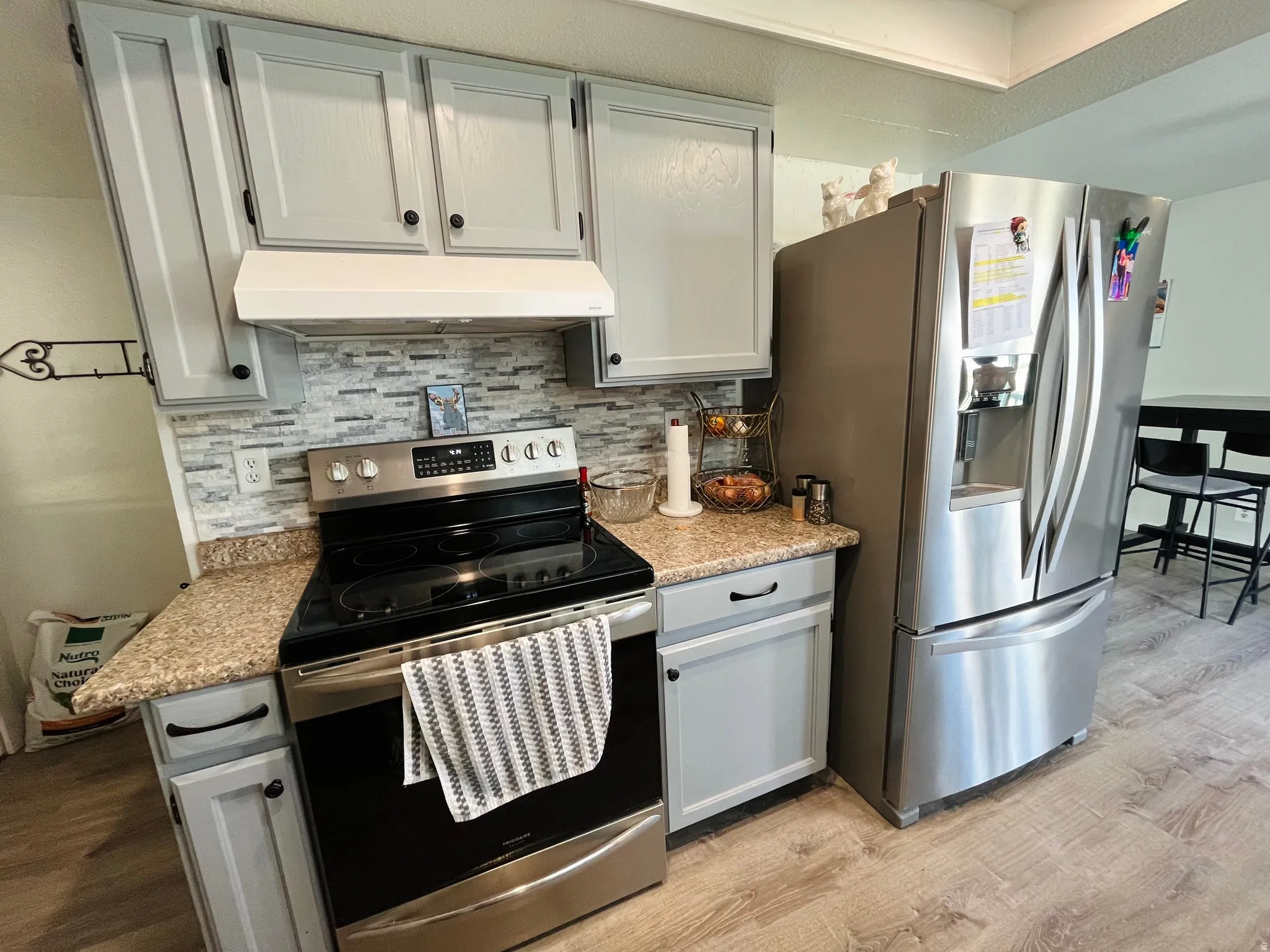 Kitchen with a convection and air fry oven, stainless steel appliances, decorative backsplash, and gray cabinetry.
