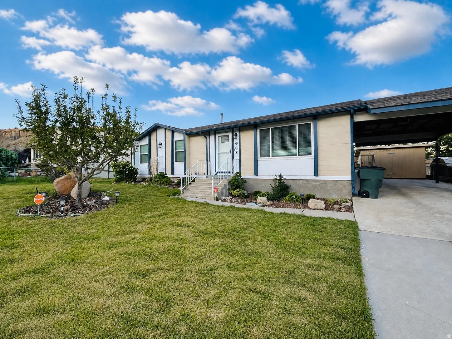 View of front of house featuring a beautifully maintained yard, concrete driveway, and an attached carport.