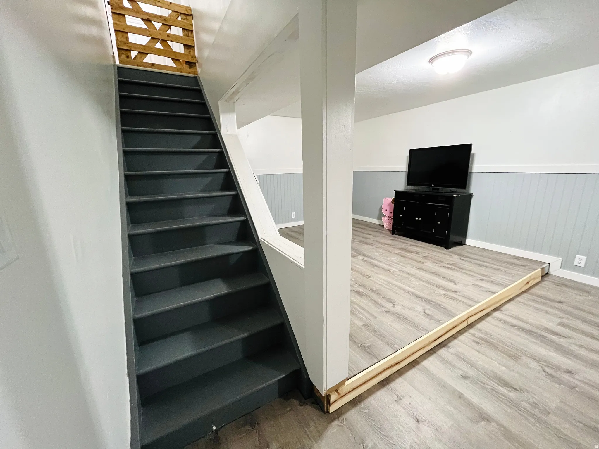 Stairway with a wainscoted wall, wood finished floors, and a textured ceiling