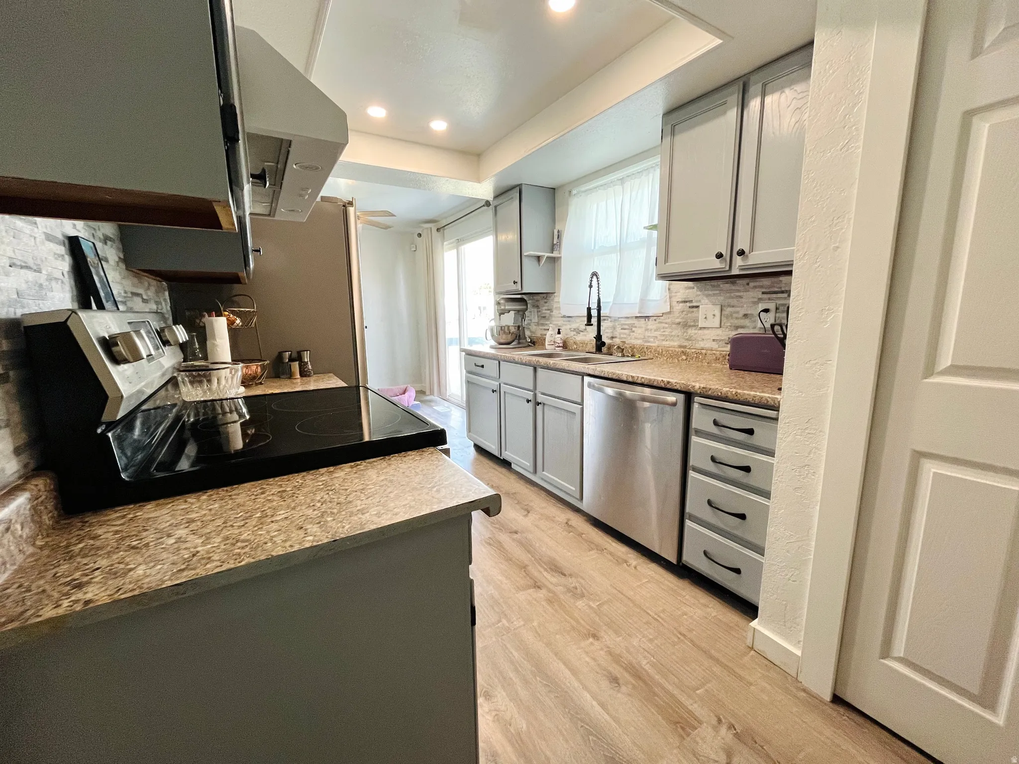 Kitchen with a convection and air fry oven, stainless steel appliances, decorative backsplash, and gray cabinetry.