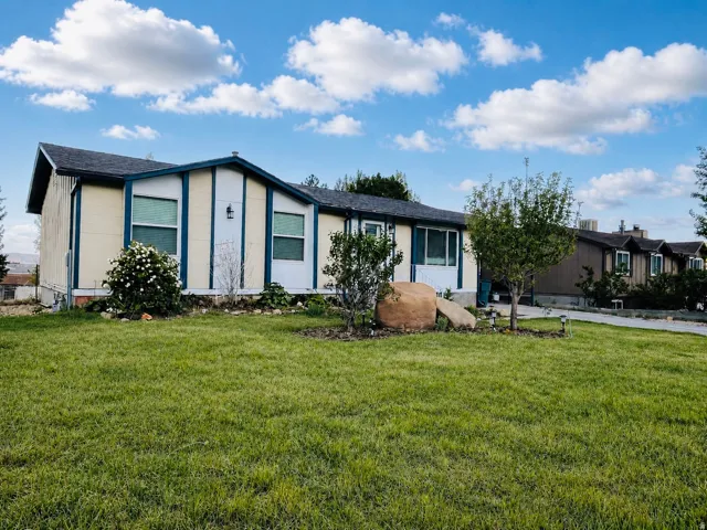 View of front of house featuring a beautifully maintained yard, concrete driveway, and an attached carport.