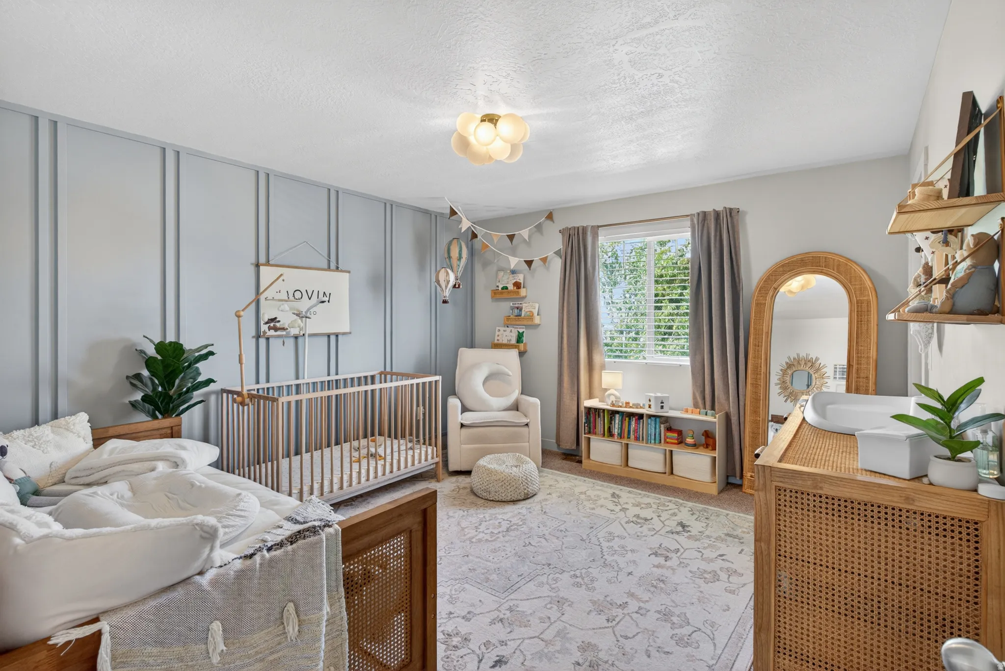 Light-filled room featuring a board and batten accent wall, recessed window with blinds, and a decorative ceiling light fixture