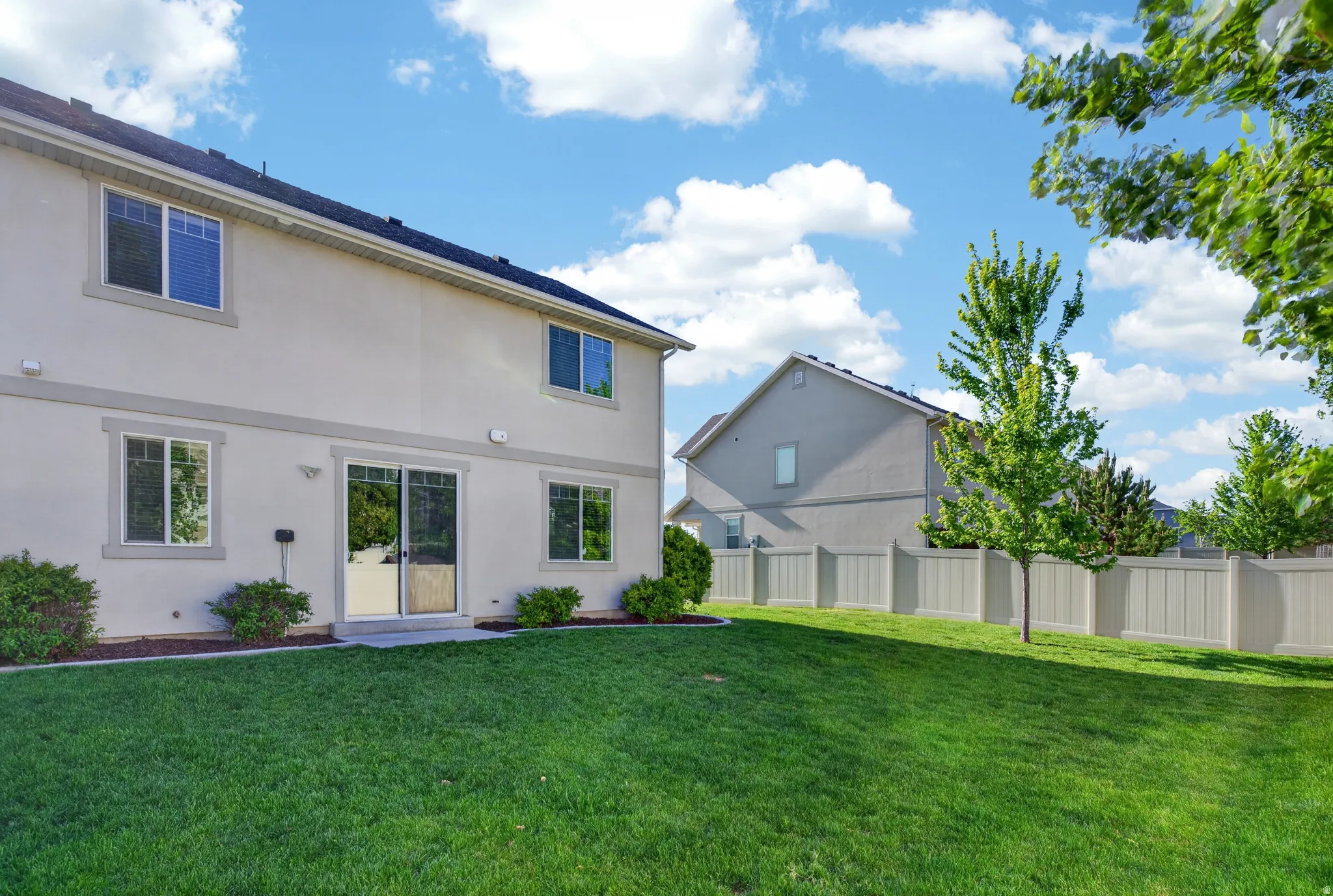 Expansive backyard featuring a manicured lawn, established trees, and a durable vinyl privacy fence