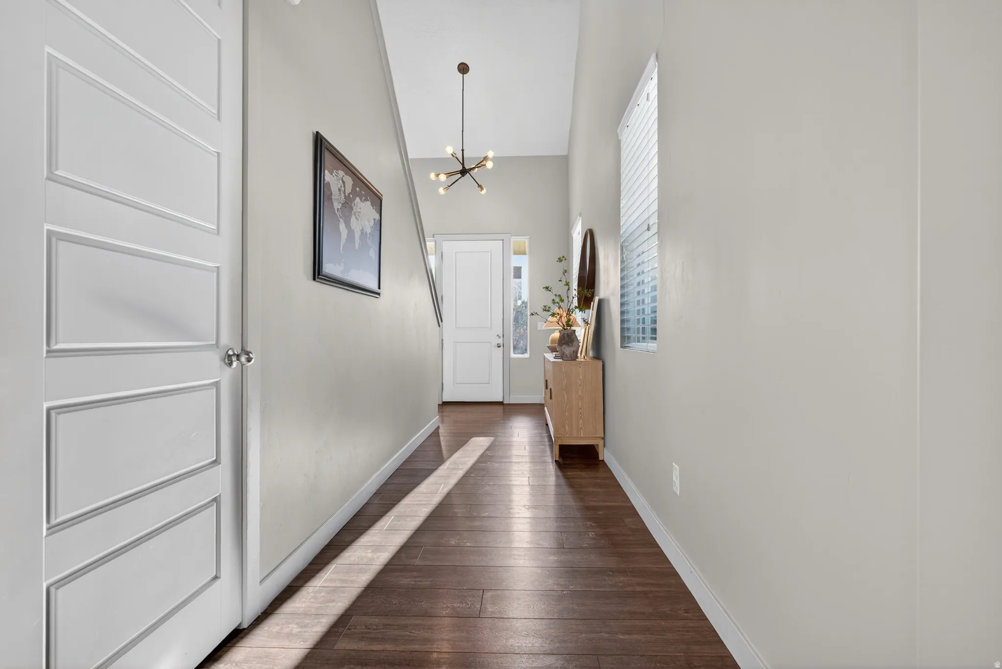 Entryway featuring wood-finish flooring, light grey walls, and a modern sputnik chandelier