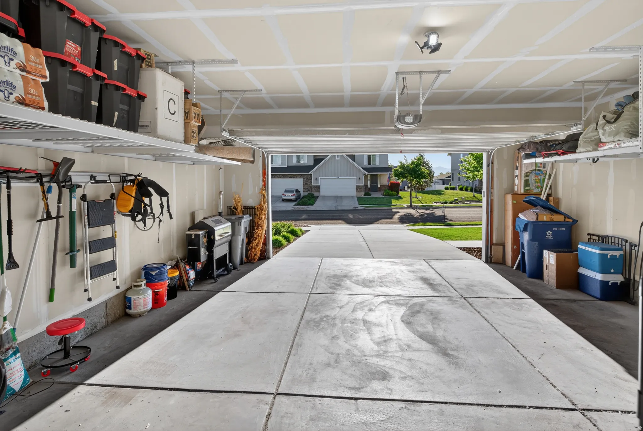 Spacious garage featuring concrete flooring, overhead storage shelving, and mounted tool organization