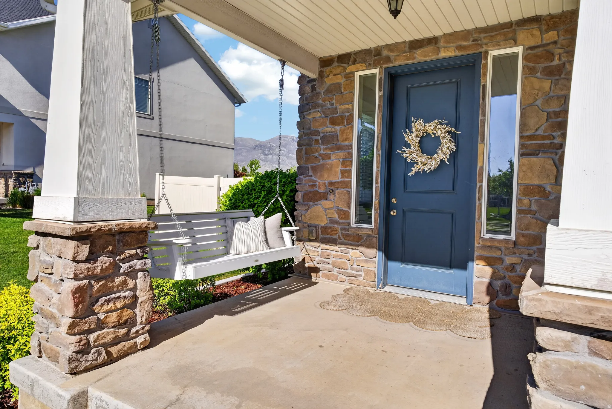 Stone veneer exterior with a contrasting blue entry door, flanked by vertical sidelight windows