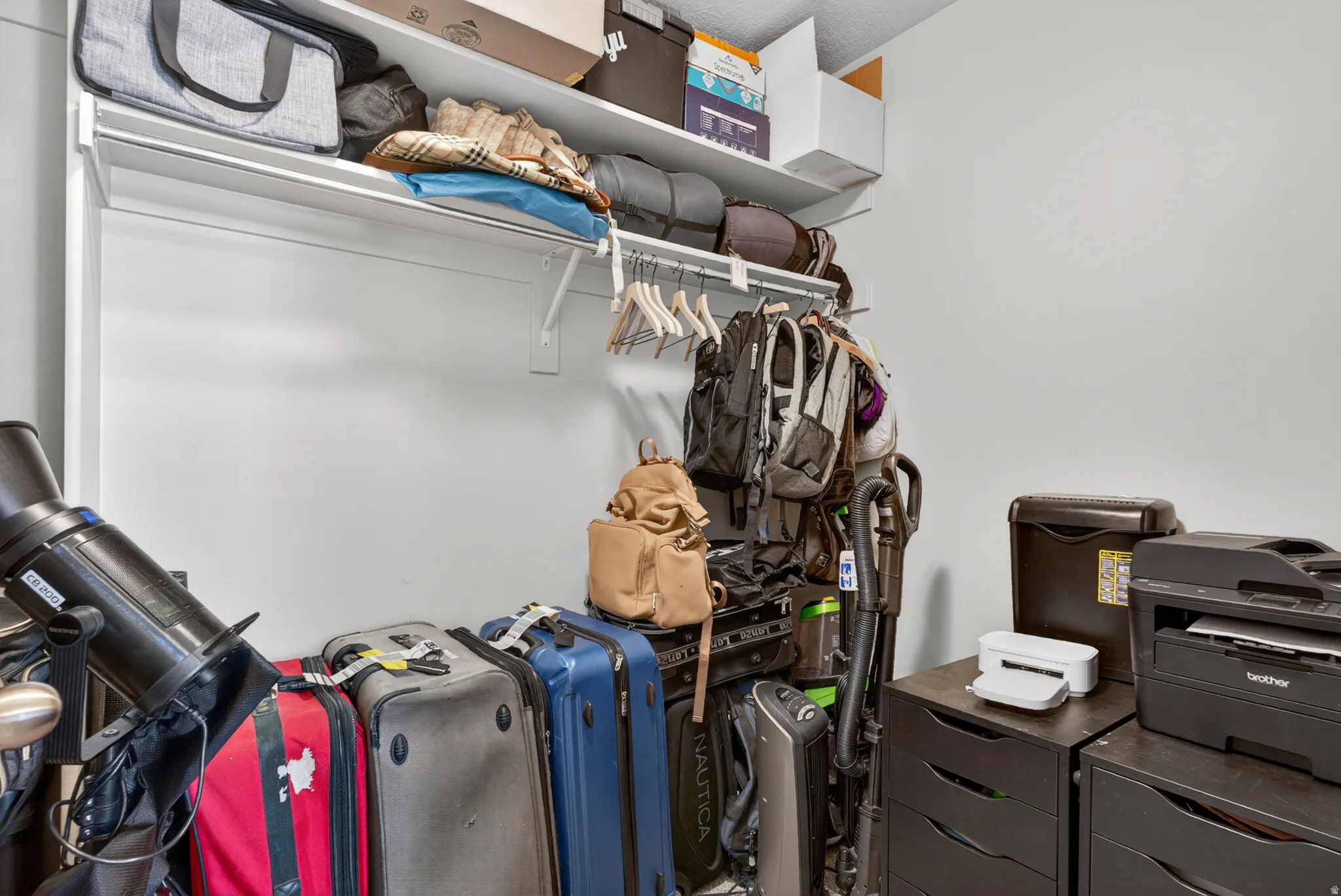 White-painted closet featuring a built-in upper shelf, a clothes hanging rod, and textured ceilings