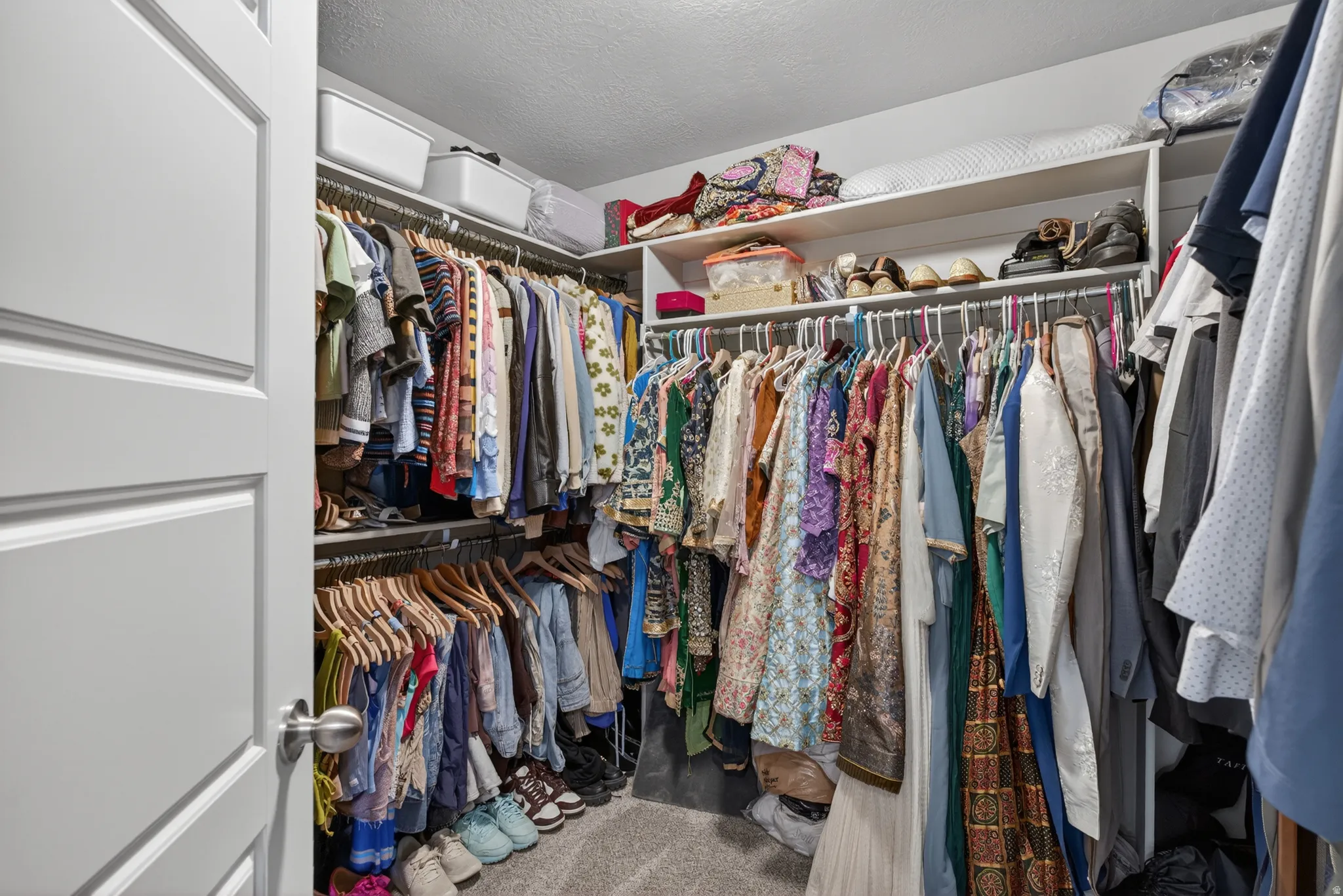 Walk-in closet featuring carpet flooring, built-in shelving, and multiple hanging rods for organization