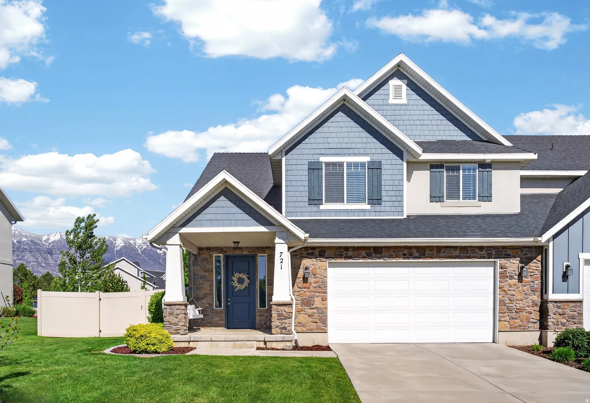Two-story residence featuring a stone and siding facade, an attached two-car garage, and a covered entry porch