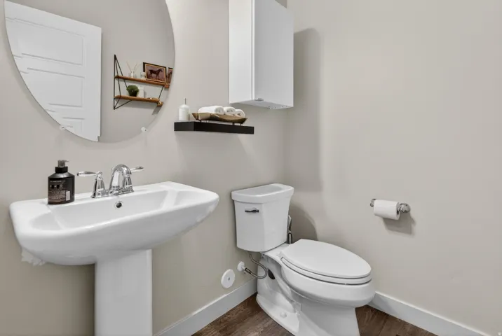 Pedestal sink with chrome fixtures and a circular wall mirror