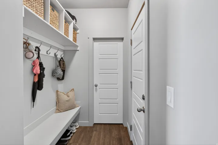 Entryway featuring wood-finish flooring, a built-in bench with integrated shelving, and a coat rack with multiple hooks