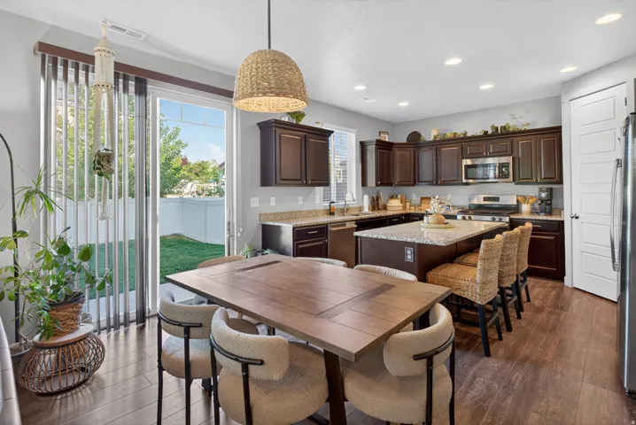Open-concept kitchen and dining area featuring rich wood-finish cabinetry, stainless steel appliances, and a central island with countertop seating
