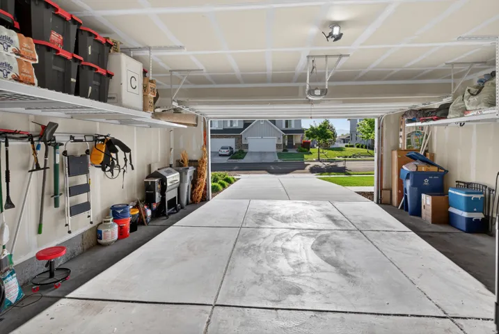 Spacious garage featuring concrete flooring, overhead storage shelving, and mounted tool organization