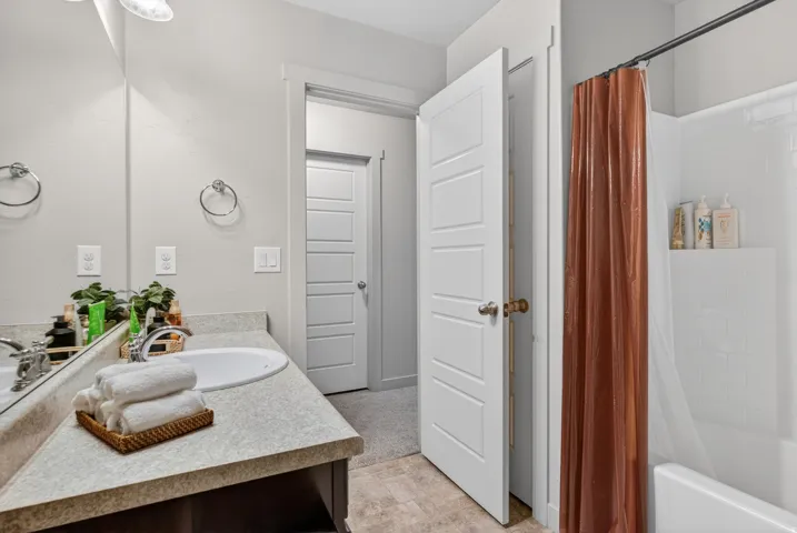 Bathroom featuring a single vanity with an integrated sink, a light-toned countertop, and a built-in bathtub with white subway tile surround