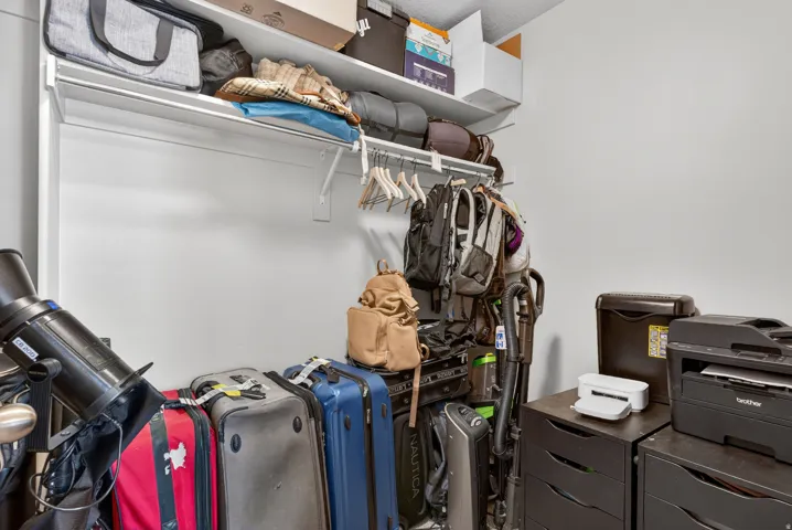 White-painted closet featuring a built-in upper shelf, a clothes hanging rod, and textured ceilings